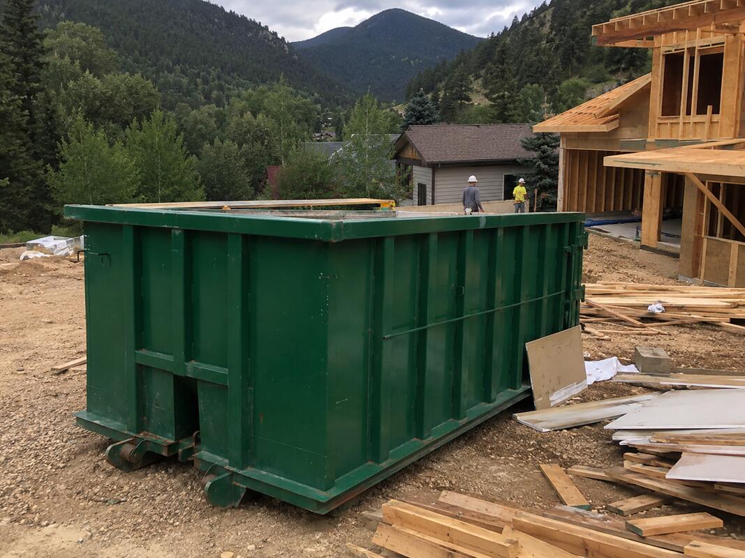 Construction dumpster rental Boone NC - roll-off container at construction site with mountain backdrop